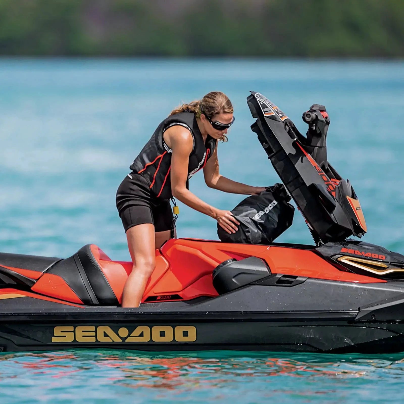 Sea-Doo waterproof dry bag 6.6 gal in black being loaded onto orange/black Sea-Doo PWC by rider