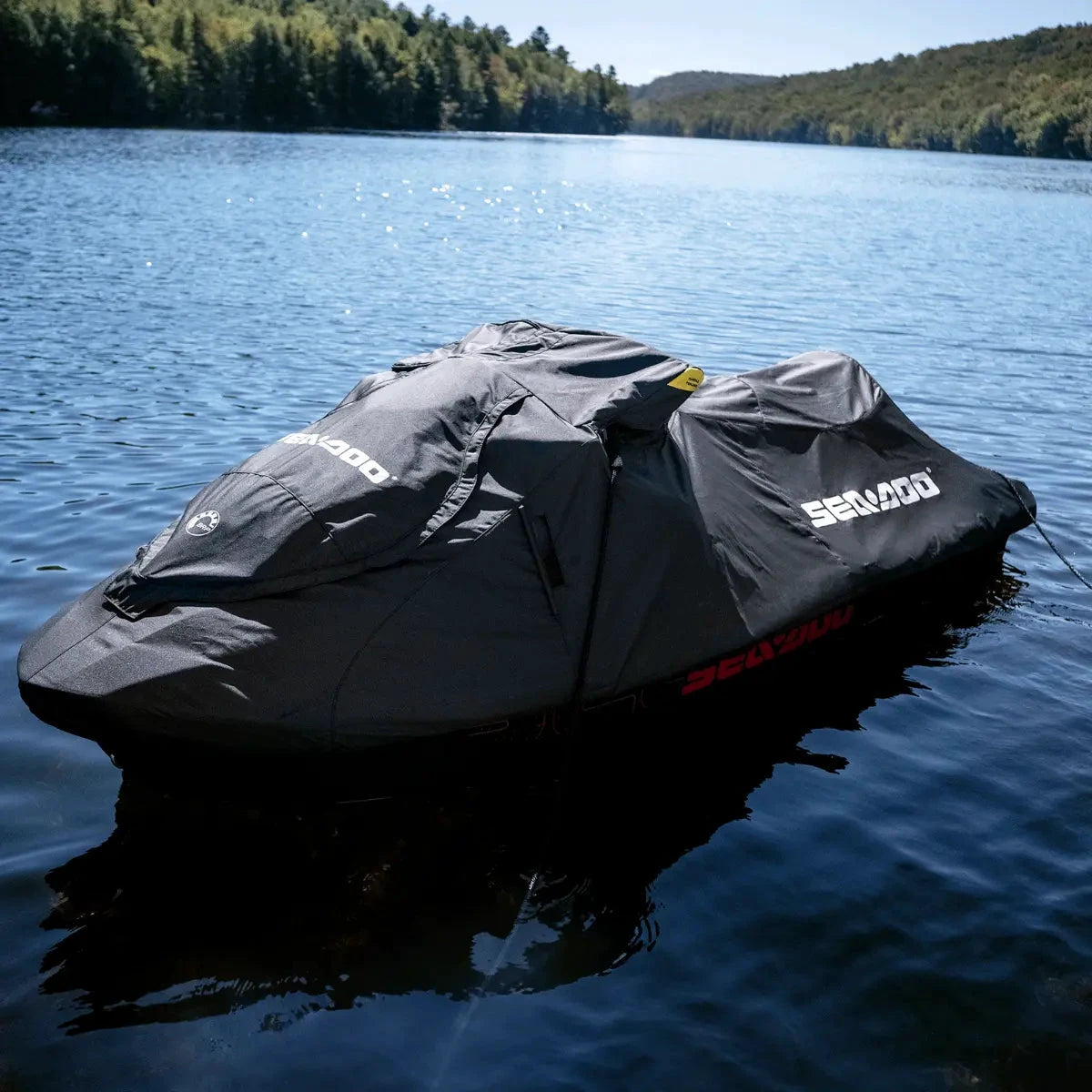 Sea-Doo PWC Cover on a black jet ski, BRP Sea-Doo branding, on a calm lake.