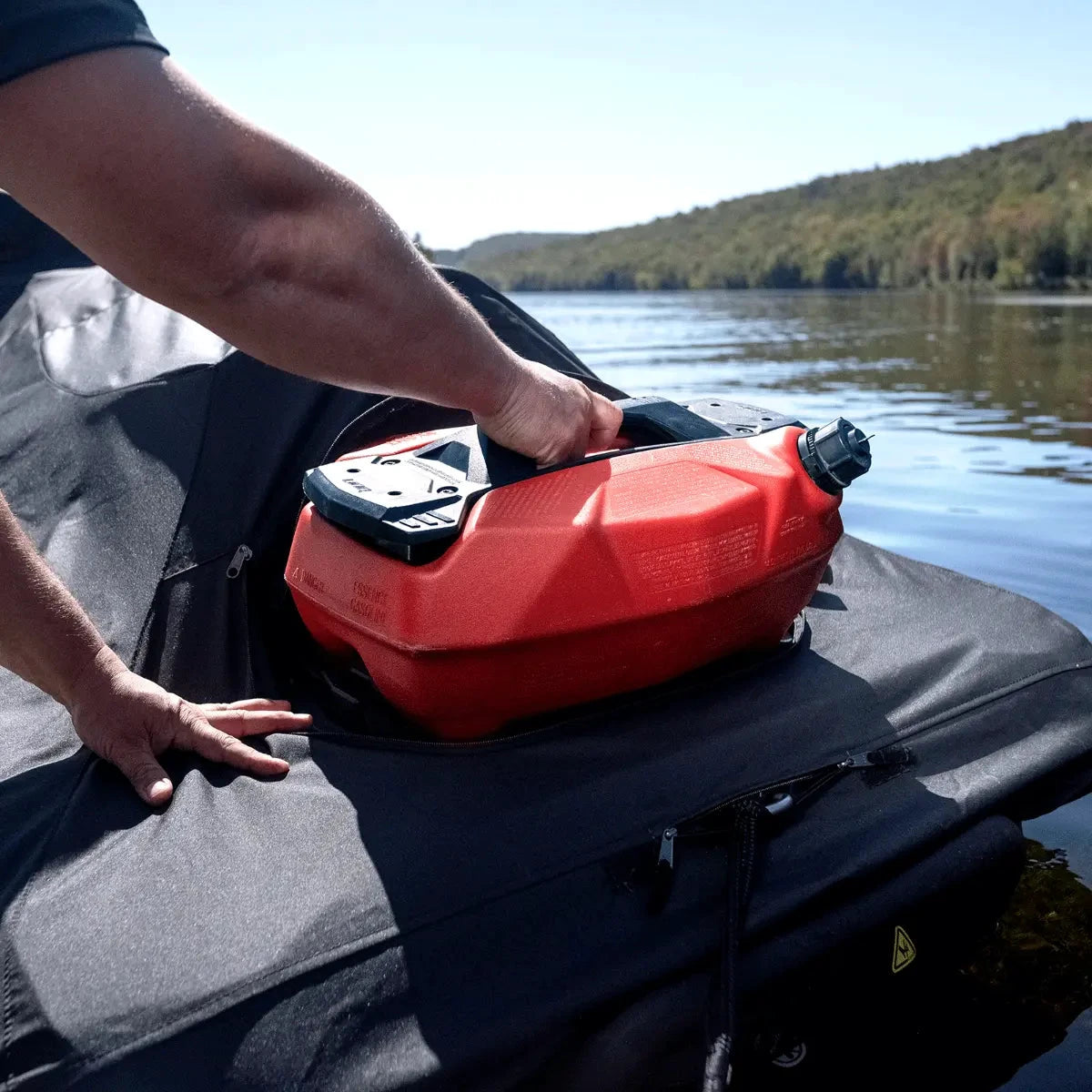 Sea-Doo PWC cover on a black boat cover with a red gas can on top beside a lake