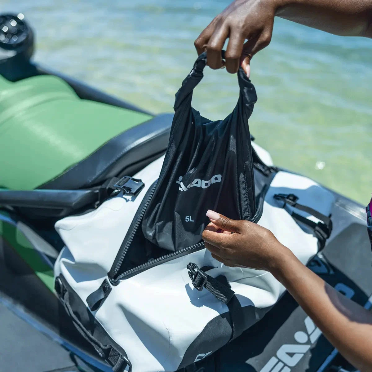 LinQ dry bag, black 5L, Sea-Doo BRP accessory, shown attached to a jet ski for on-water storage.