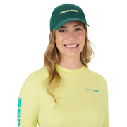 Sea-Doo Signature Cap baseball cap, green with gold Sea-Doo embroidery, shown on a smiling model wearing a lime-yellow top