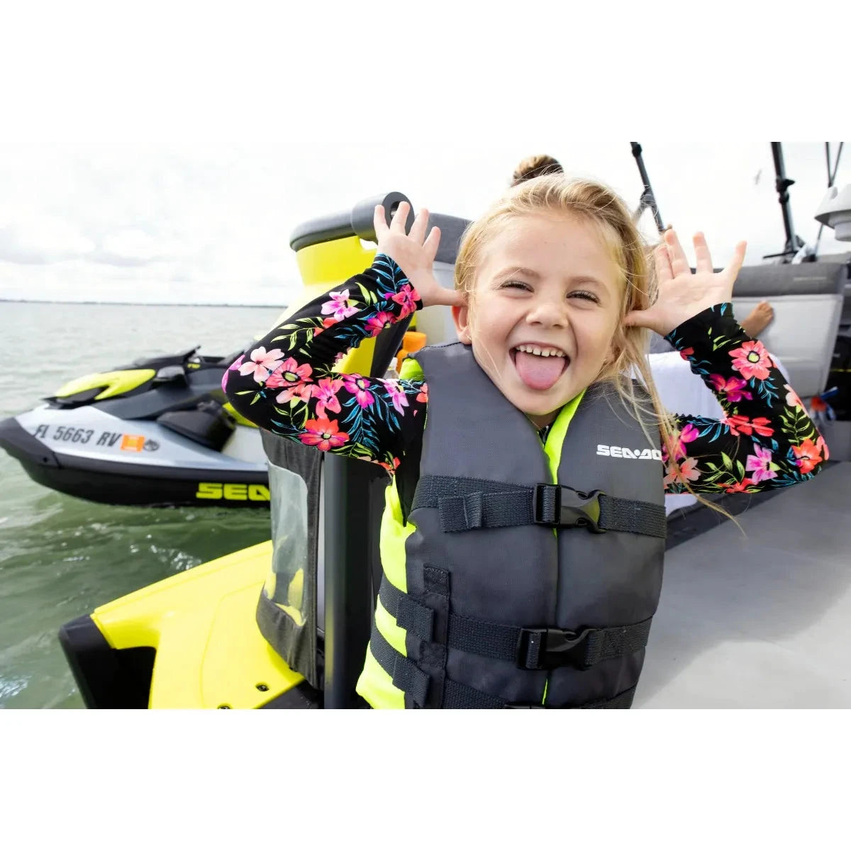 Sea-Doo kids' Sandsea PFD life jacket in gray with neon yellow accents worn by a child on a Sea-Doo watercraft